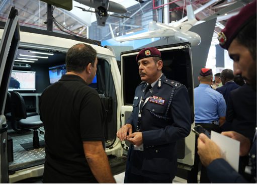 A man in a black shirt is talking to a man in a blue uniform. Description generated by AI