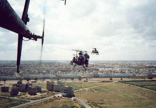 A helicopter is flying over a city with a large building below it. Description generated by AI