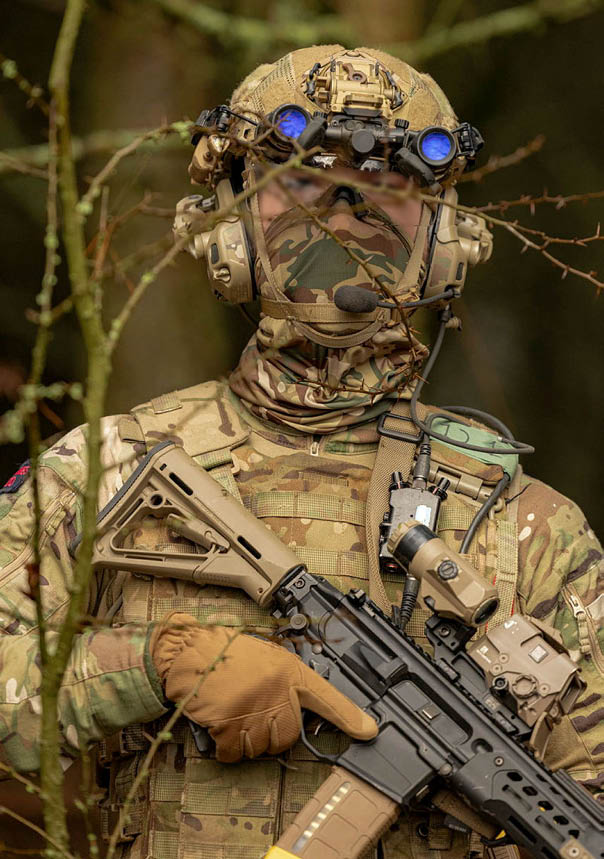 A man wearing a camouflage uniform and holding a gun. Description generated by AI