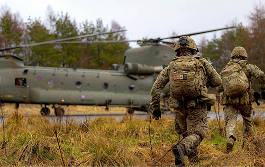 Two men walking in a field with a helicopter in the background. Description generated by AI