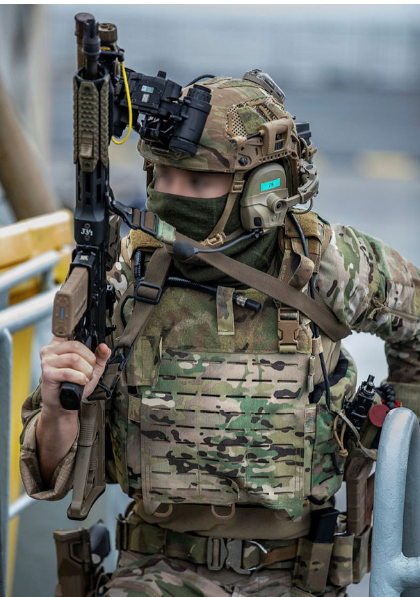 A man wearing a camouflage uniform and holding a gun. Description generated by AI