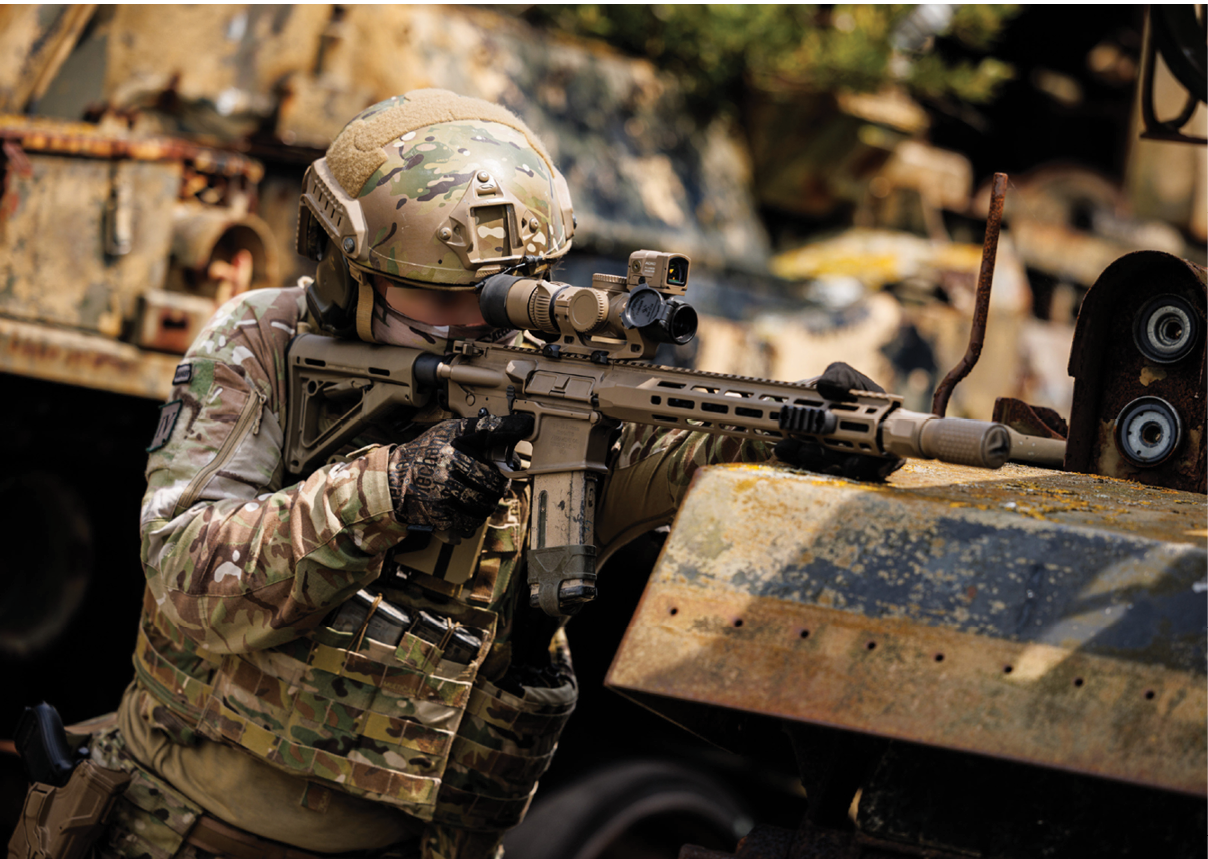 A man in a camouflage uniform holding a gun. Description generated by AI