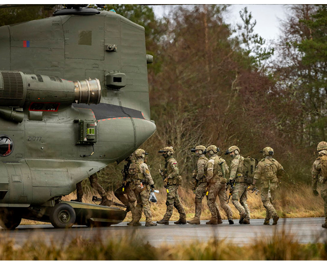 A group of soldiers are walking in front of a helicopter. Description generated by AI