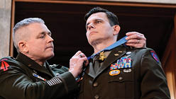 A man is receiving a medal from another man. Description generated by AI