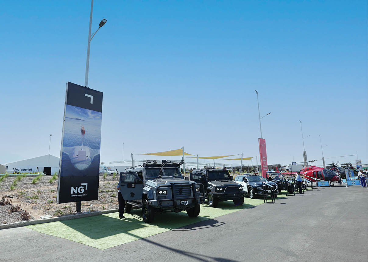 A row of four military vehicles are parked on the side of a road. Description generated by AI
