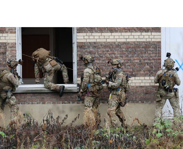 A group of men in camouflage uniforms are climbing out of a window. Description generated by AI