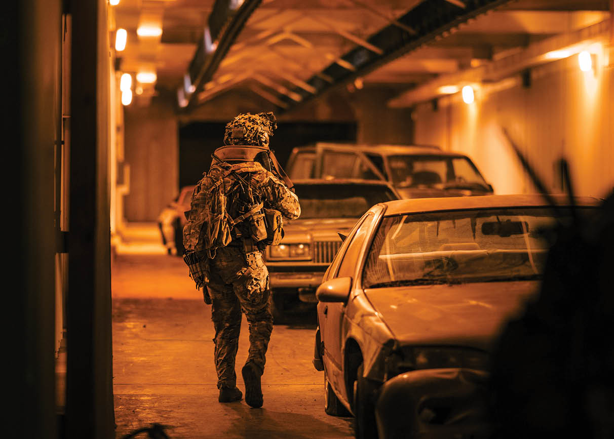 A man in camouflage walking down a hallway. Description generated by AI