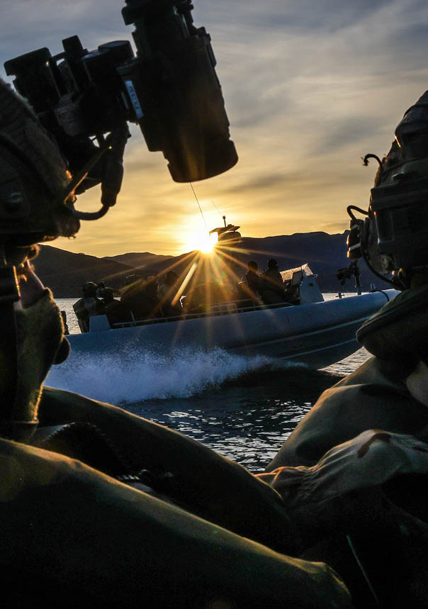 Two men in camouflage uniforms are looking at the sunset. Description generated by AI