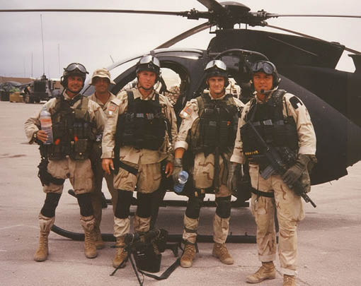 A group of soldiers standing in front of a helicopter. Description generated by AI