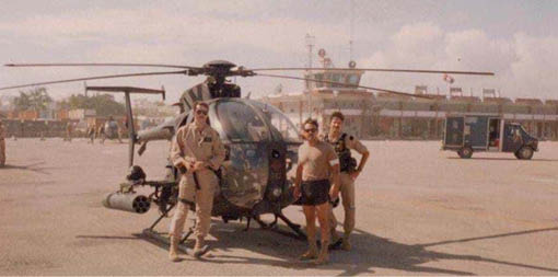 Three men standing in front of a helicopter. Description generated by AI