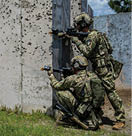 Two men in camouflage are playing a video game. Description generated by AI
