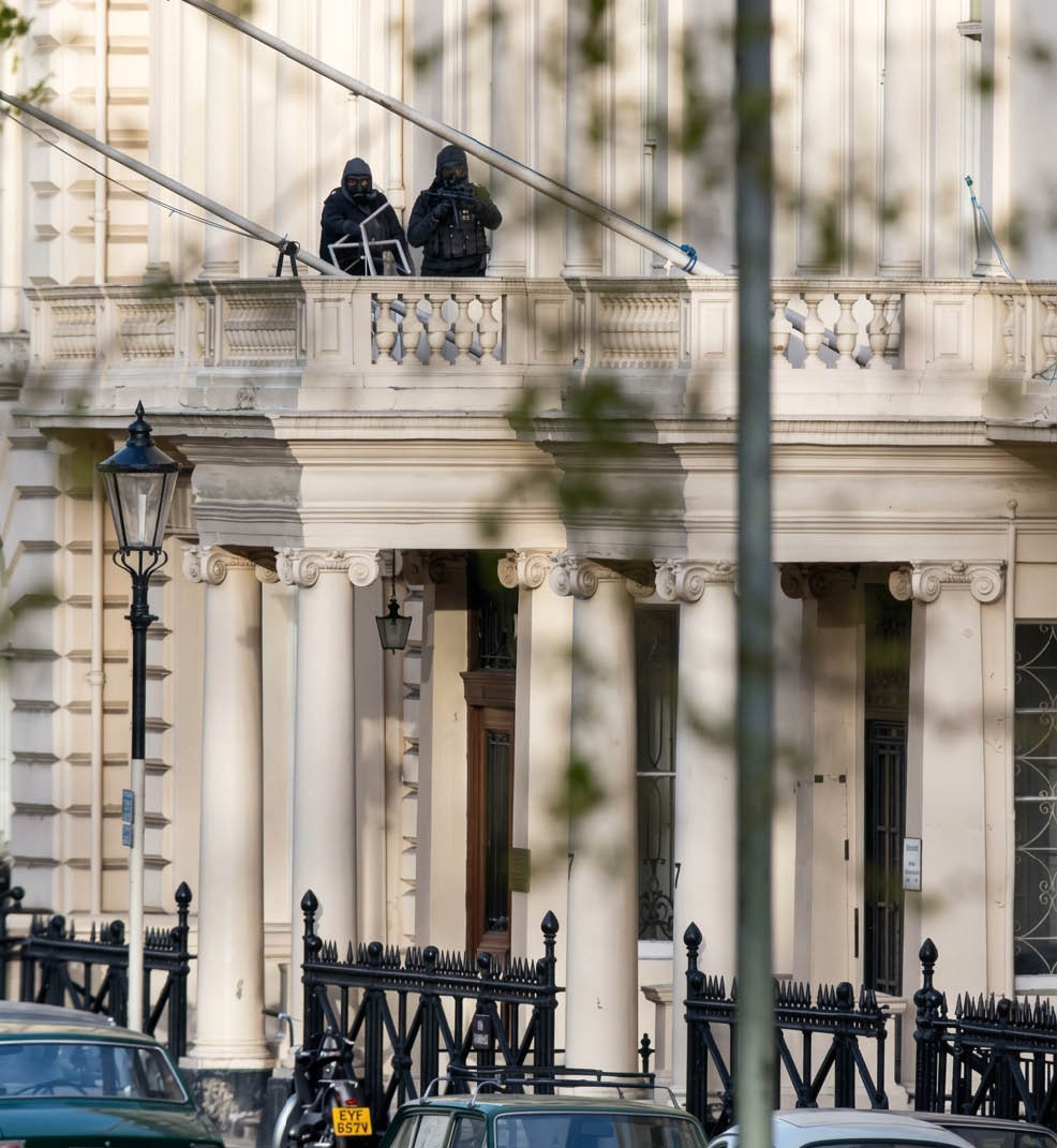 A close-up view of classical architectural columns with ornate capitals and a hanging lantern in front of a building facade. Description generated by AI
