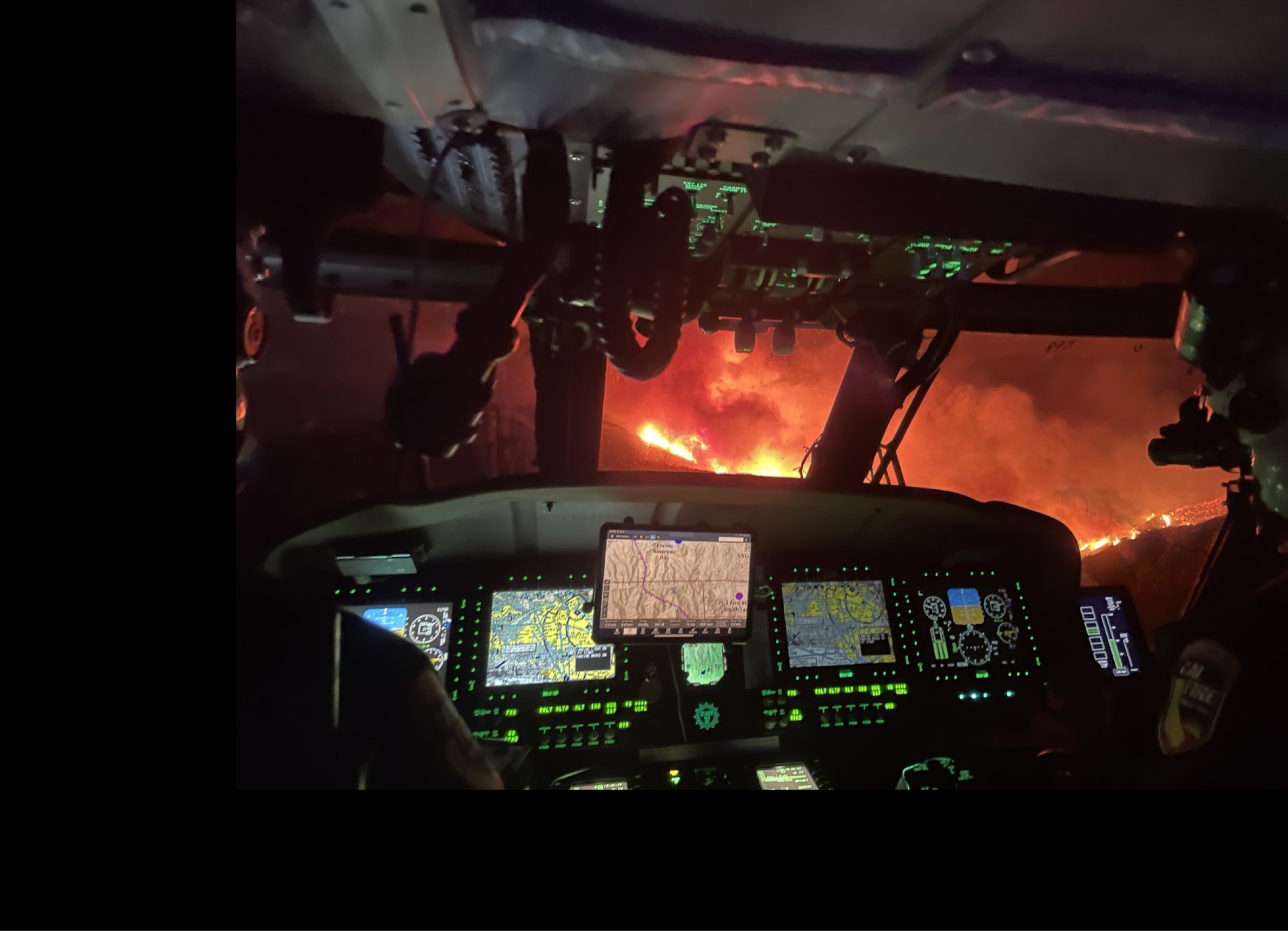A cockpit of a helicopter with a fire in the distance. AI generated content