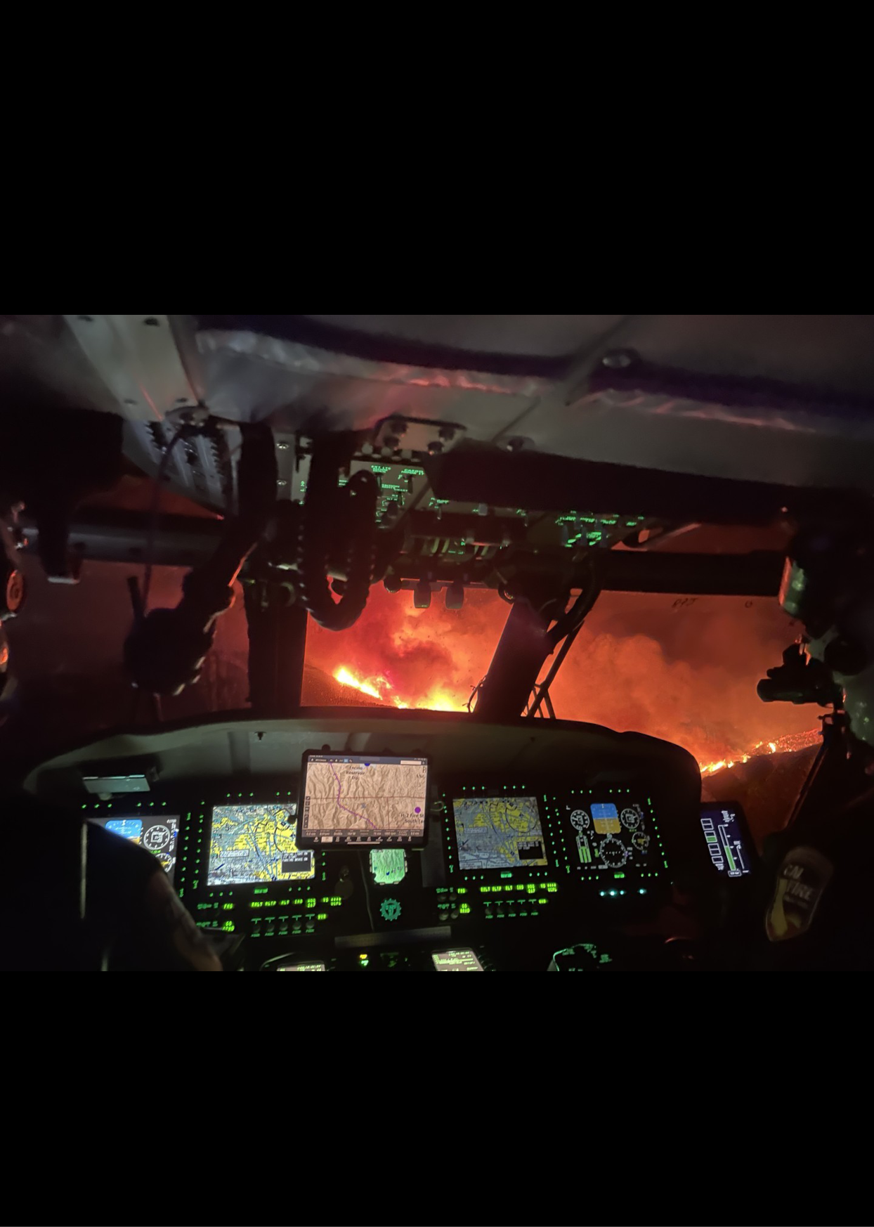 A cockpit of a helicopter with a fire in the distance. AI generated content
