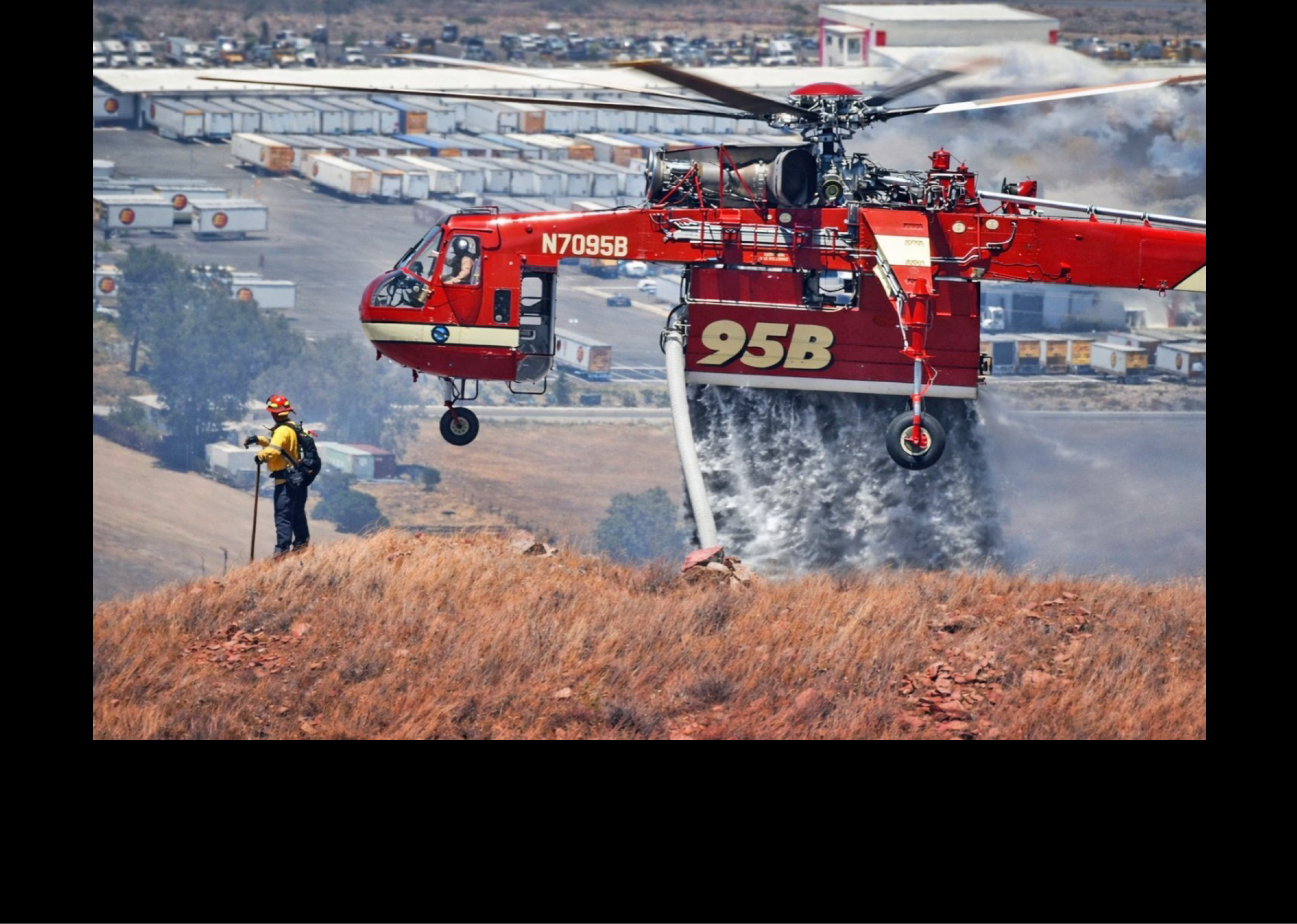 A red helicopter is flying over a field with a man standing in the grass. AI generated content