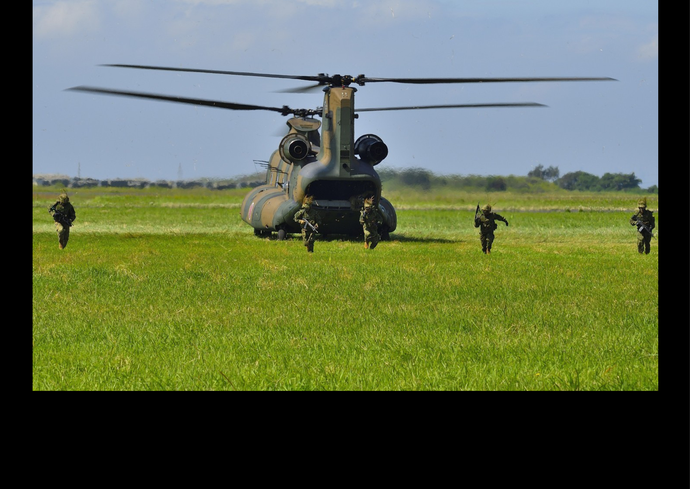 A group of soldiers are walking through a grassy field, with one of them carrying a gun. A helicopter is flying above them, possibly providing support or surveillance. AI generated content