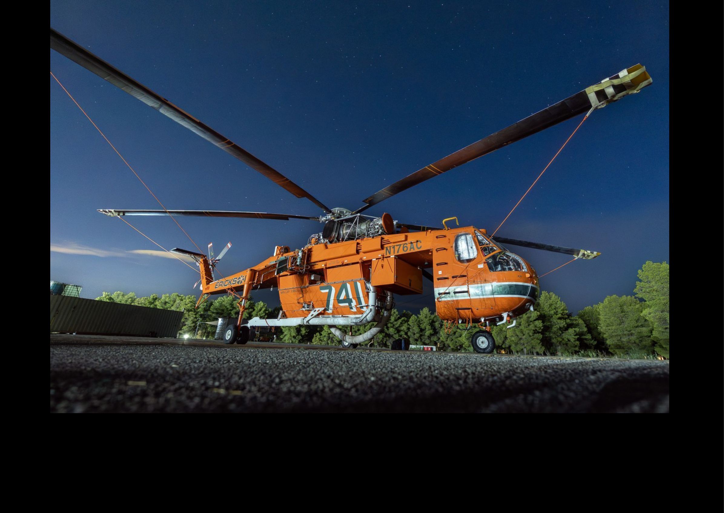 A large orange helicopter with a number 67 on it is parked on the ground. AI generated content