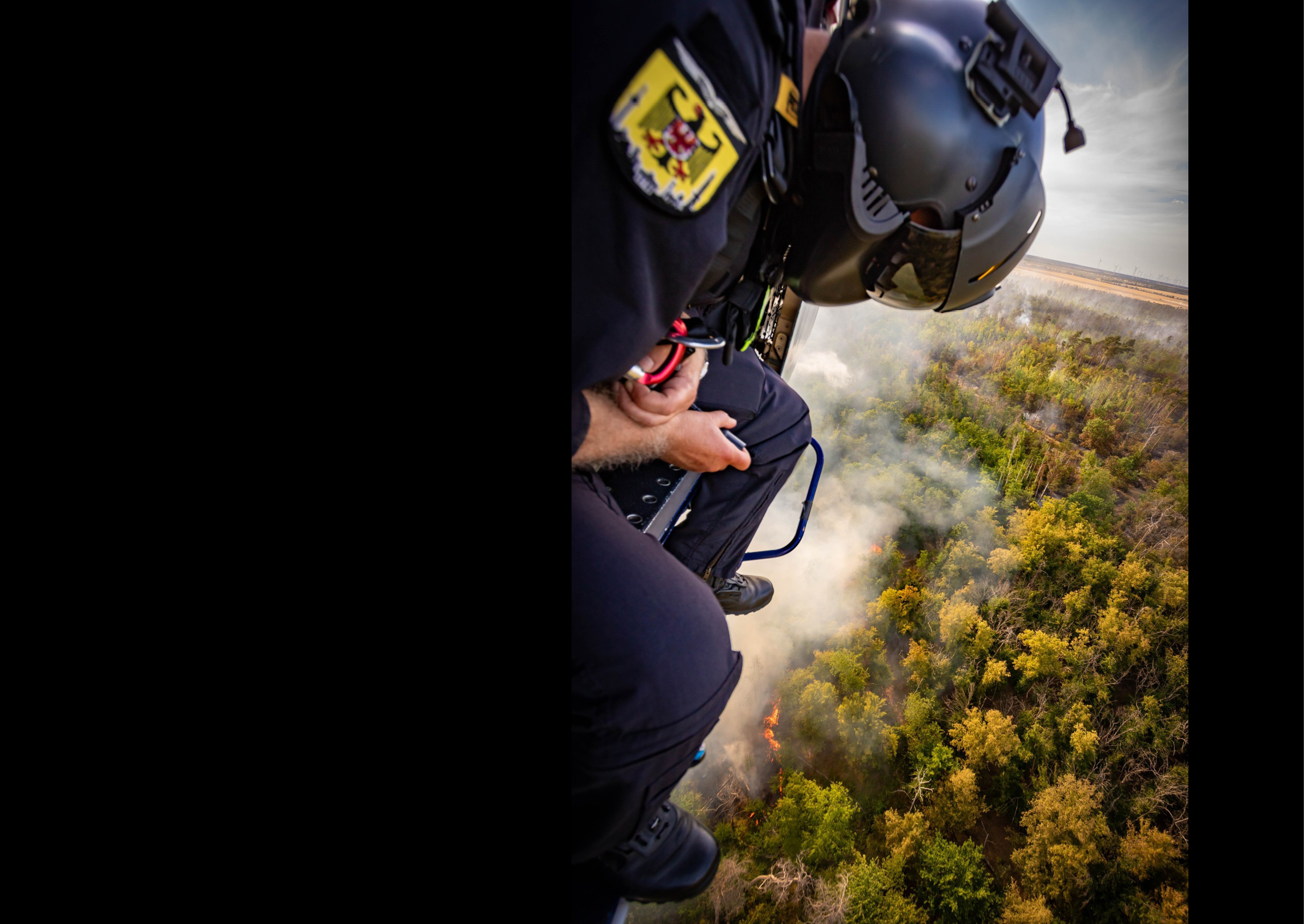A man in a helicopter flying over a forest with a fire below. AI generated content