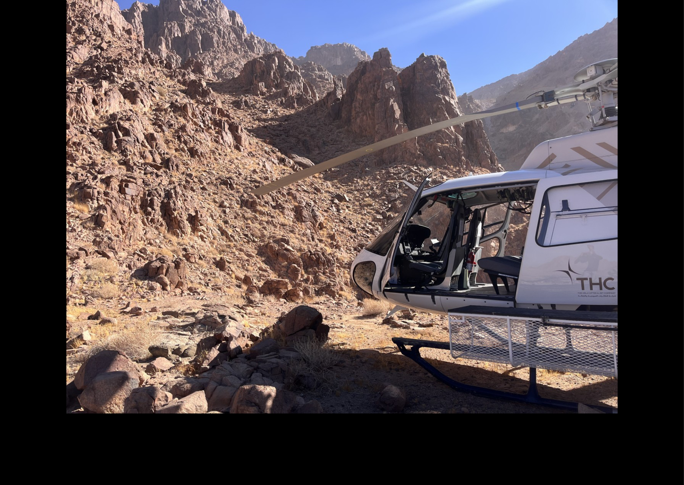 A helicopter is parked on a rocky hillside, with a mountain in the background. AI generated content
