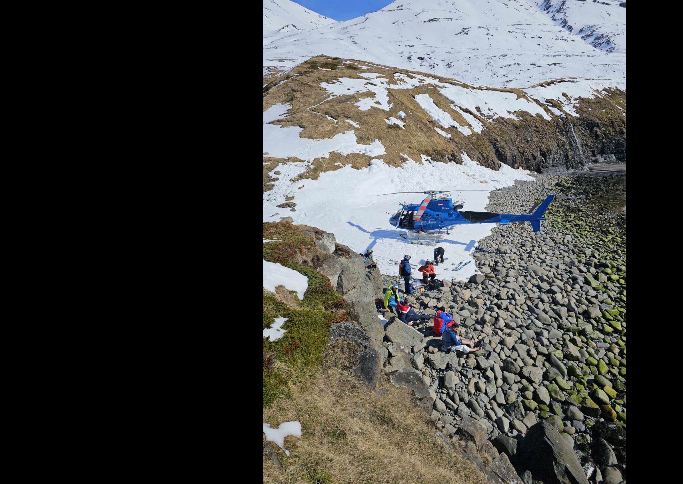 A group of people are sitting on rocks near a helicopter. AI generated content