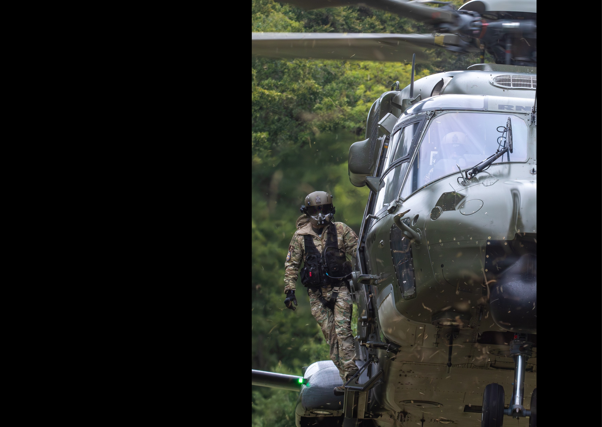 A man in a camouflage uniform is standing on the side of a helicopter. AI generated content