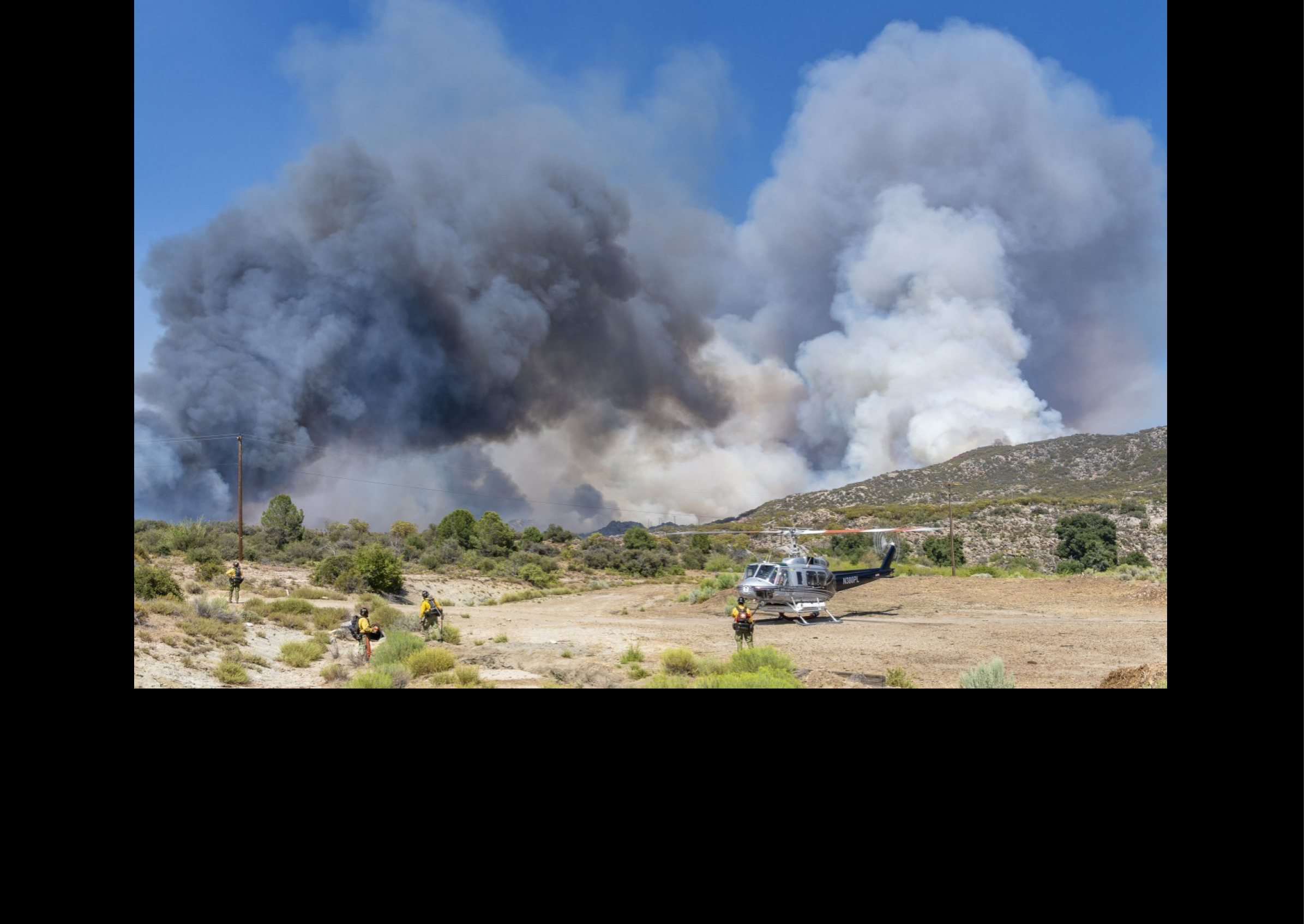 A group of firefighters are standing in front of a fire. AI generated content