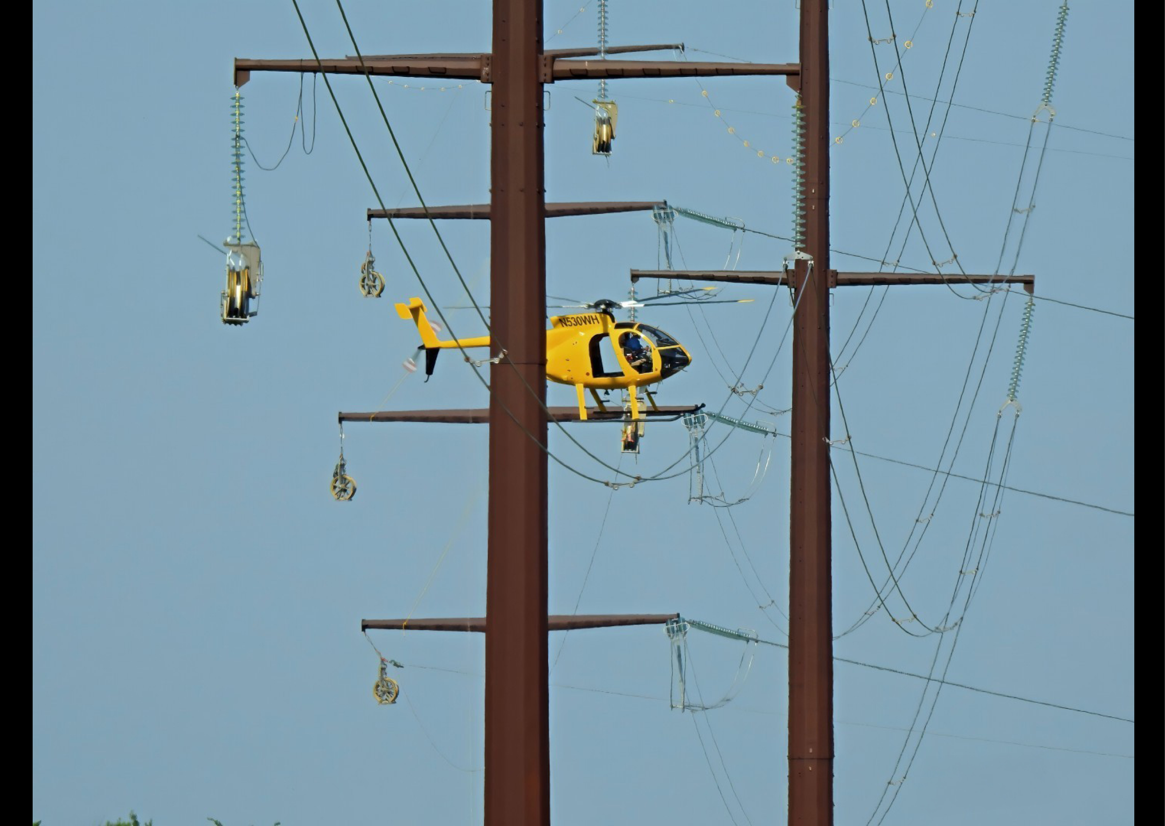 A yellow helicopter is flying near power lines. AI generated content
