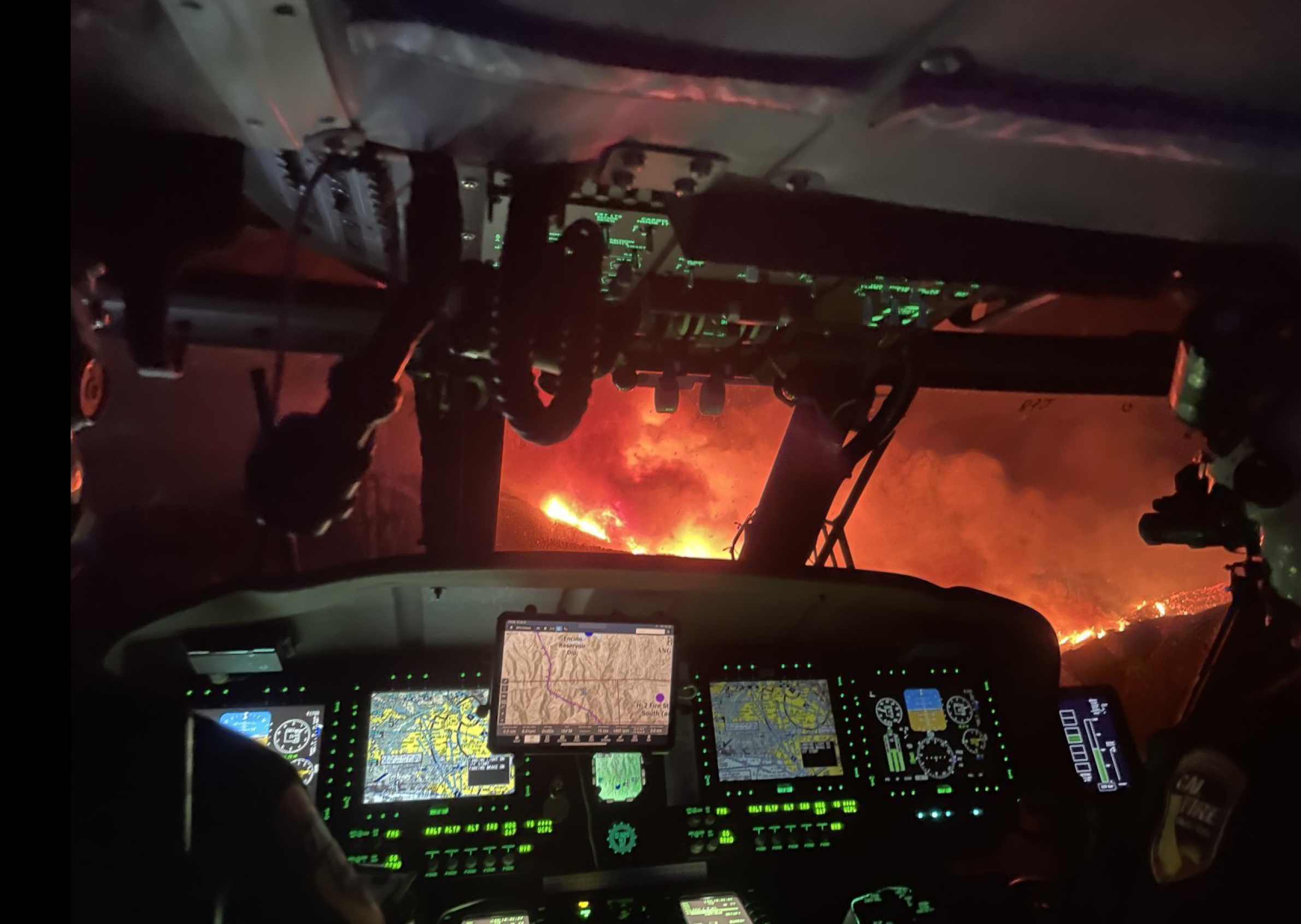 A cockpit of a helicopter with a fire in the distance. AI generated content