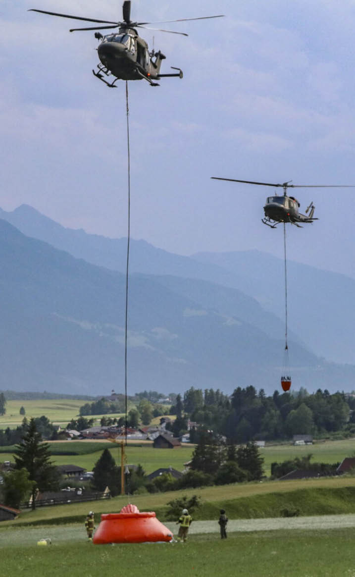 A helicopter is flying over a mountain range, dropping a red object. AI generated content
