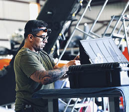 A man wearing a green shirt is working on a laptop. AI generated content