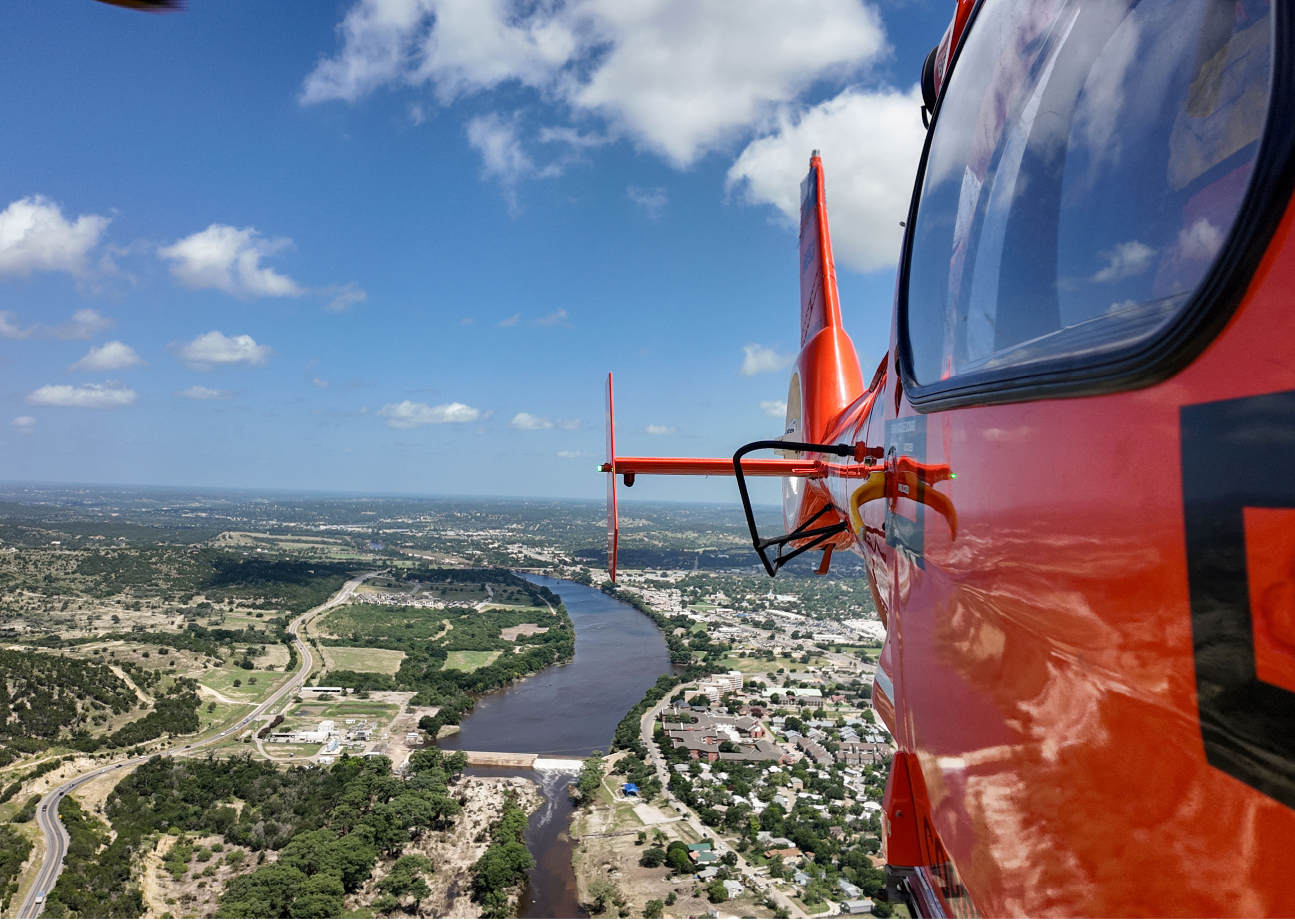 A U.S. Coast Guard MH-65 Dolphin helicopter aircrew conducts a flyover, July 10, 2025, above Kerrville, Texas. The aircrew was relieved shortly afterward by an incoming aircrew to maintain a continuous asset presence in the wake of the catastrophic flash flooding near Kerrville. (U.S. Coast Guard photo by Petty Officer 3rd Class Carmen Caver)