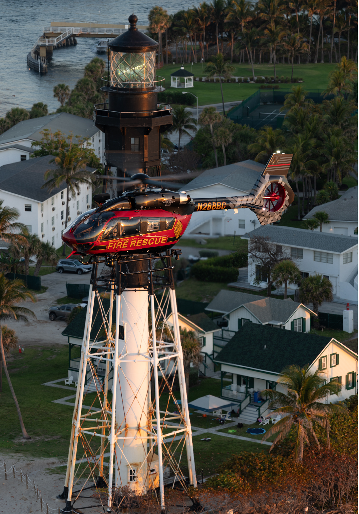 A helicopter is flying over a lighthouse, with a house in the background. AI generated content