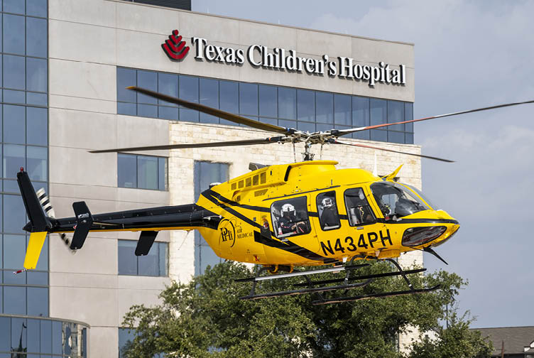 A yellow helicopter is flying over a building with the words “Texas Children's Hospital" on it. AI generated content
