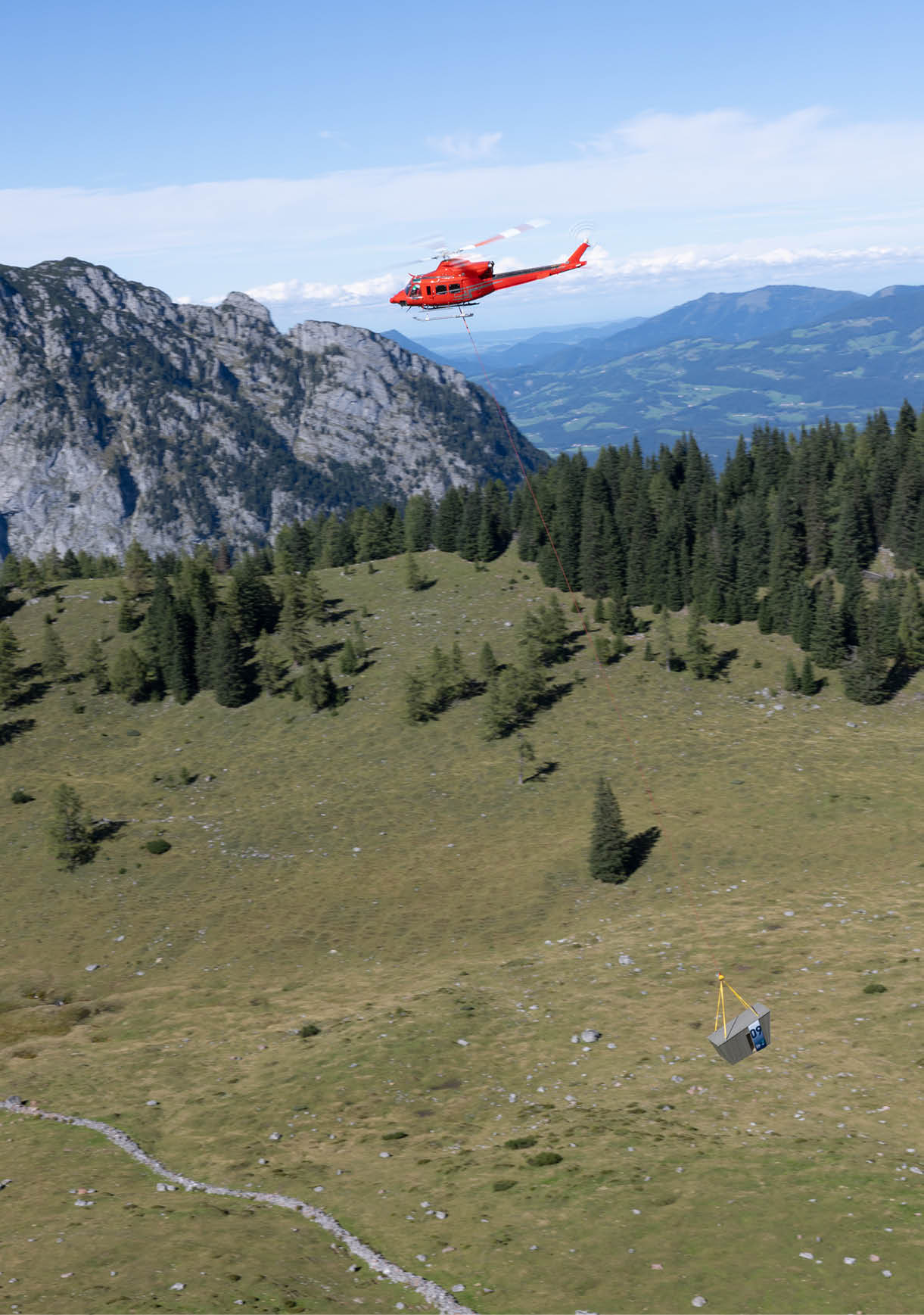 A red helicopter is flying over a grassy hillside. AI generated content