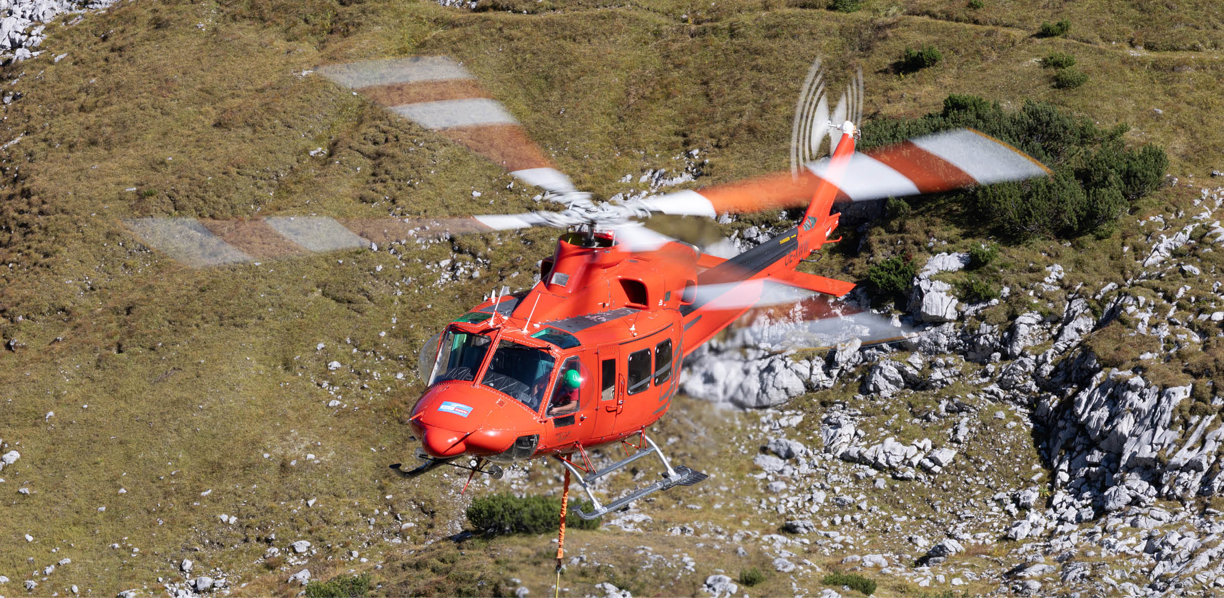 A red helicopter is flying over a rocky area. AI generated content