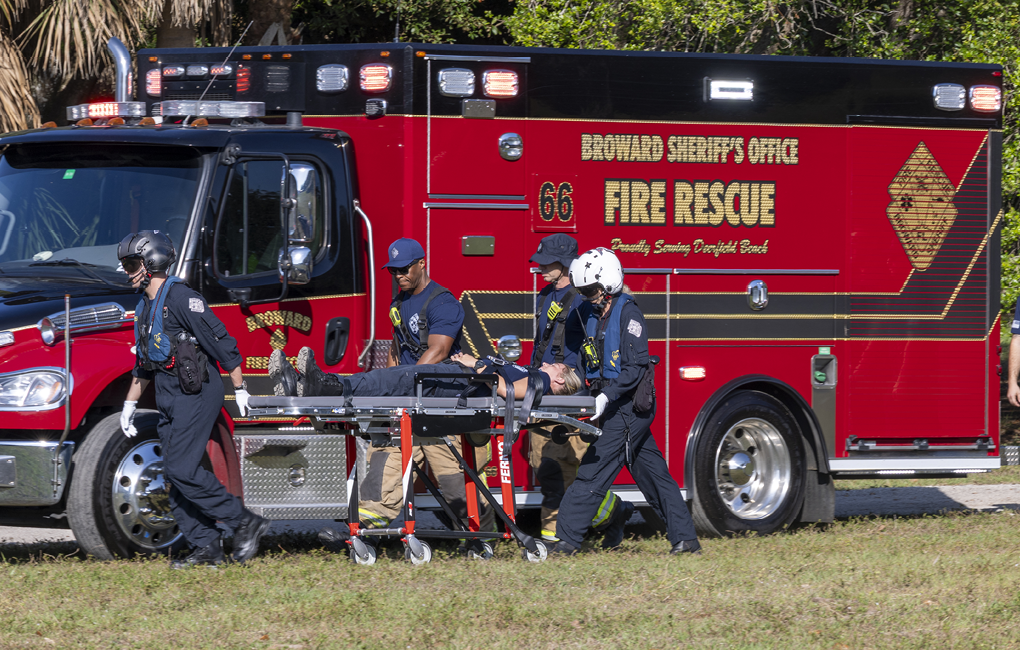 A group of people are working together to load a person onto a red ambulance. AI generated content