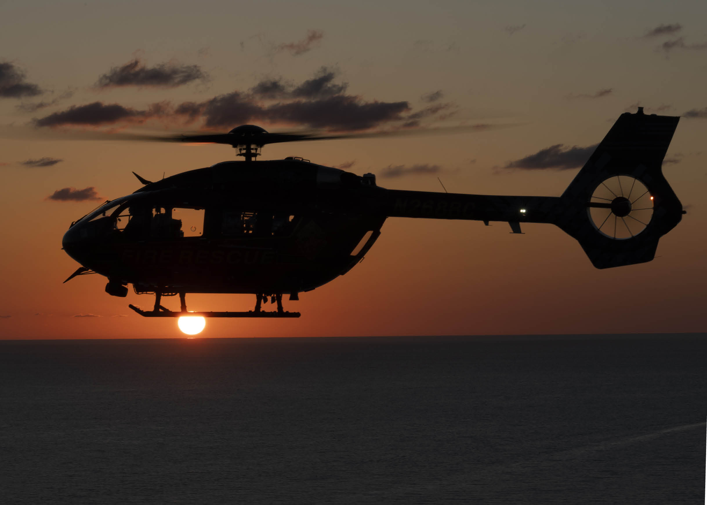 A helicopter is flying over the ocean at sunset. AI generated content