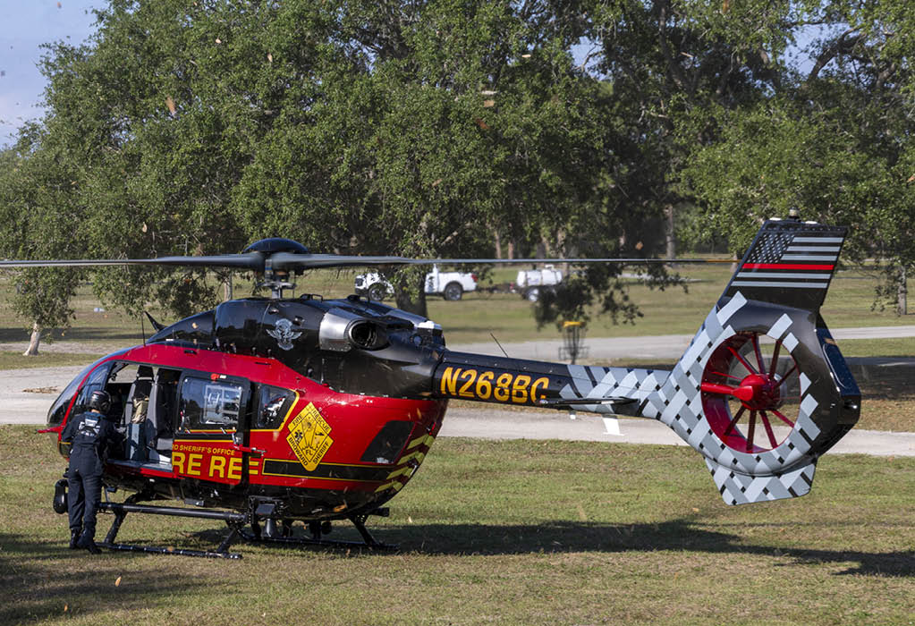 A red and yellow helicopter is parked on the grass. AI generated content