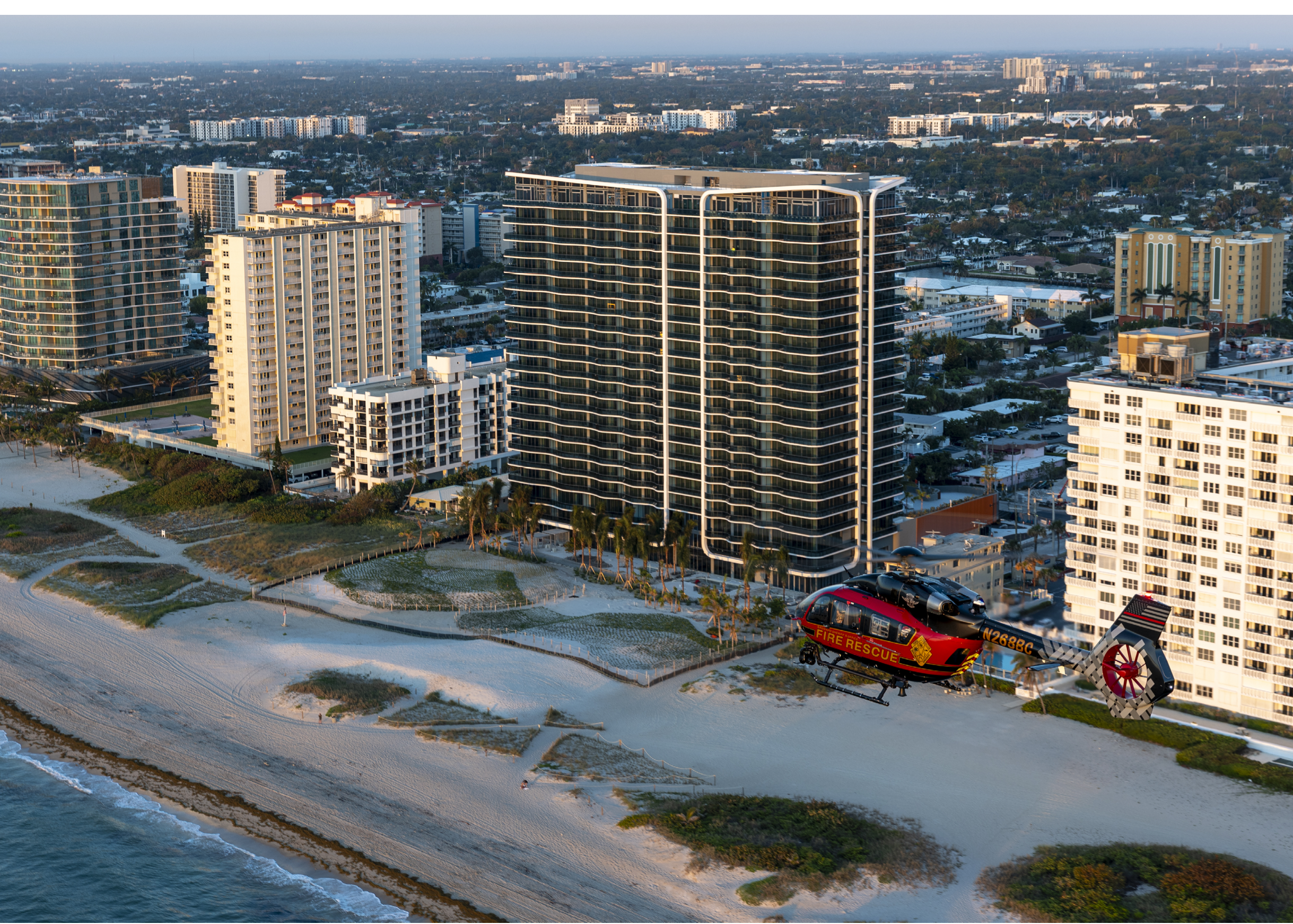 A helicopter is landing on a beach near a city. AI generated content
