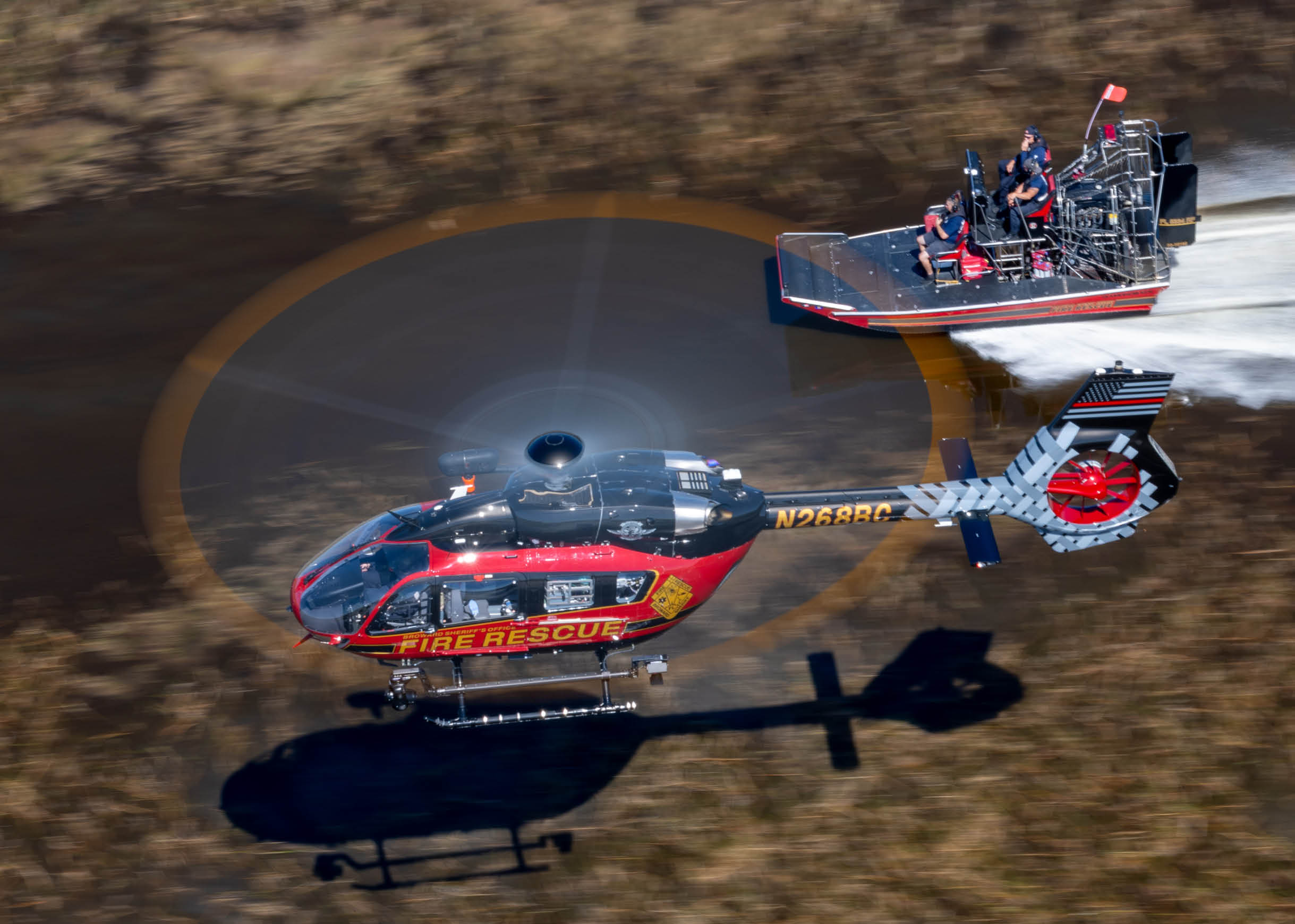 A red and black helicopter is flying over a boat in the water. AI generated content