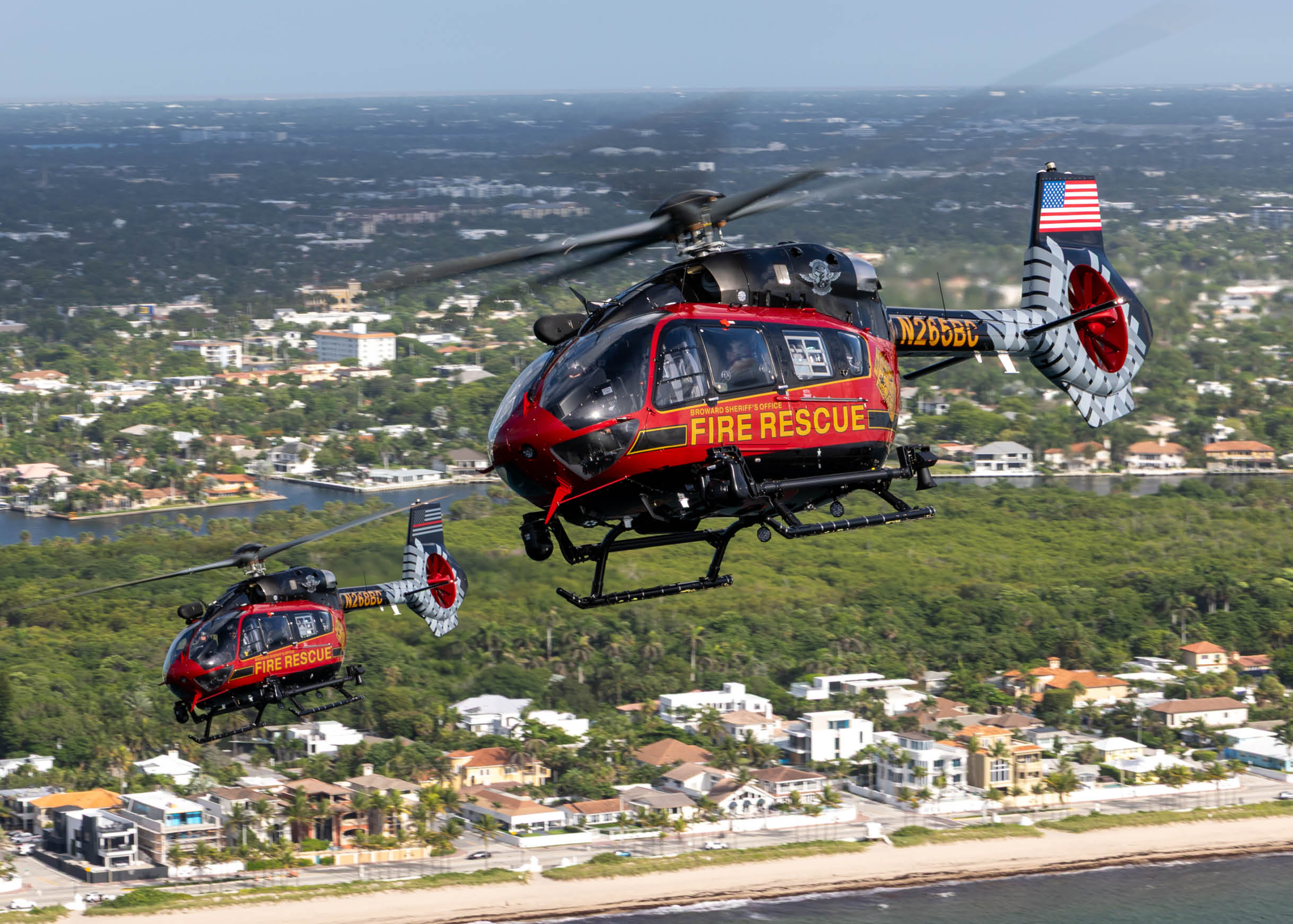 Two helicopters are flying over a beach with a city in the background. AI generated content