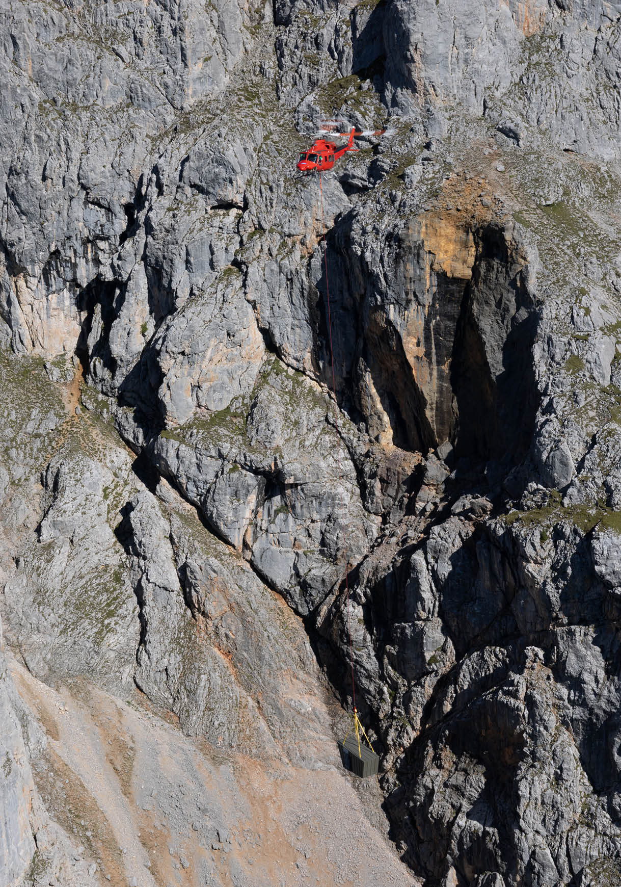 A red helicopter is flying over a mountain with a large rocky cliff. AI generated content