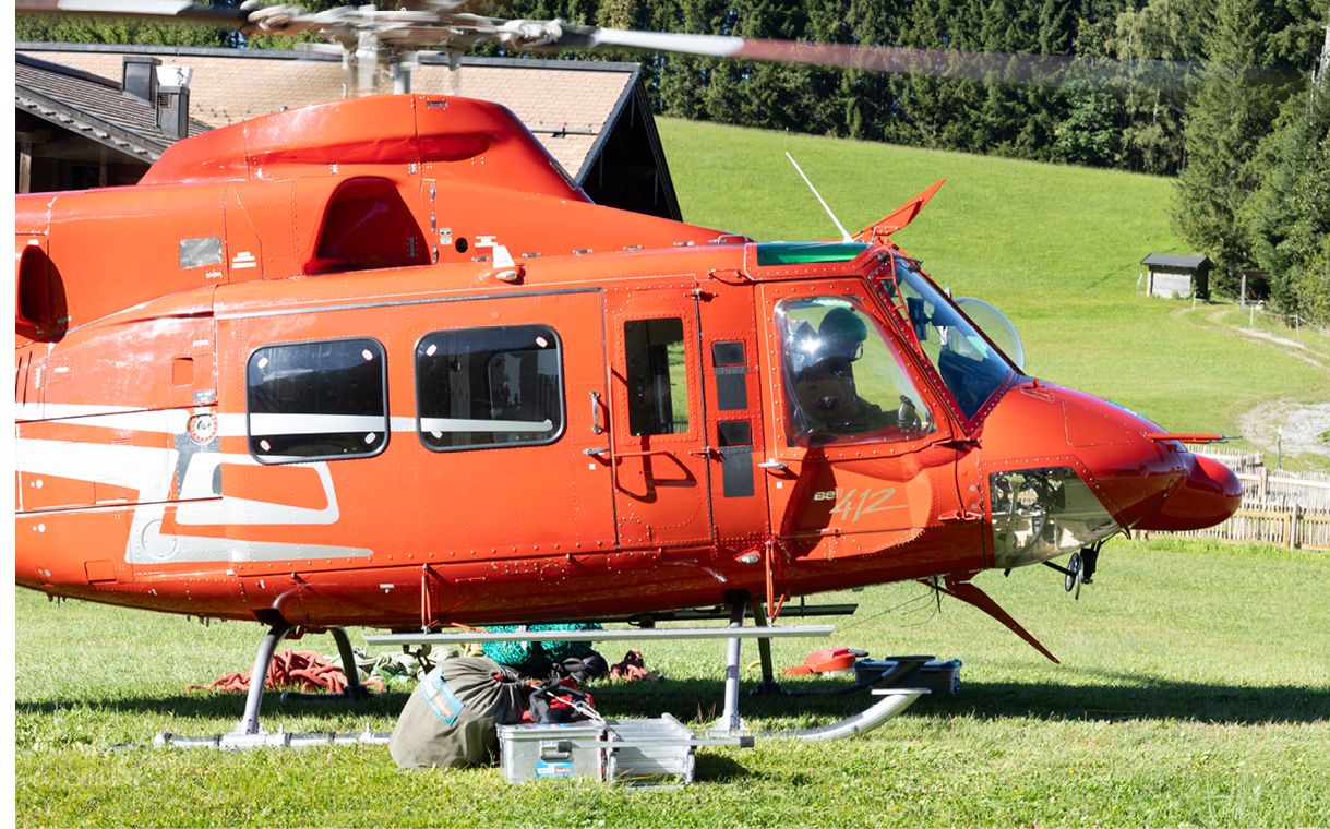 A red helicopter is parked on a grassy field. AI generated content