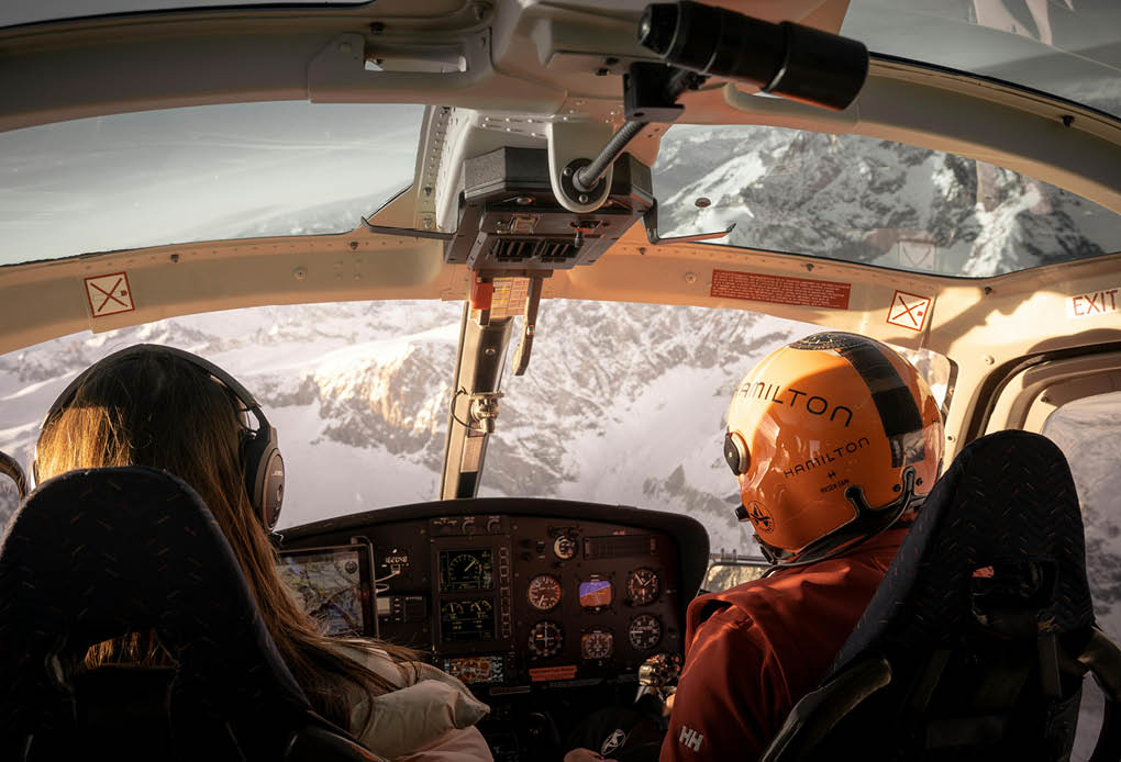 A man and a woman are sitting in a helicopter, enjoying the view of the mountains. AI generated content