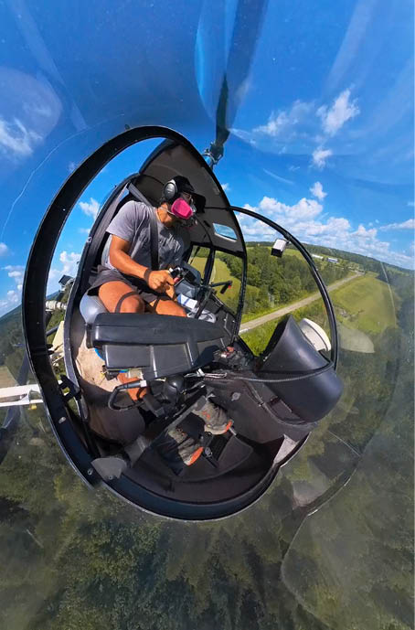 A person is sitting in a helicopter, flying over a lush green hillside. AI generated content