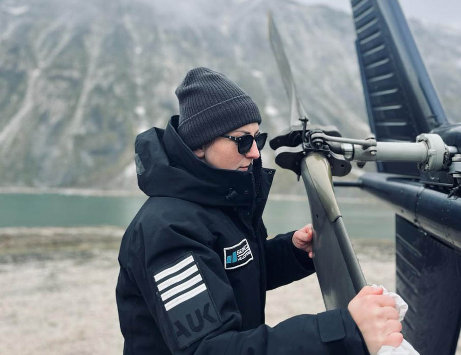 A woman wearing a black jacket and a beanie hat is holding onto a helicopter blade. AI generated content