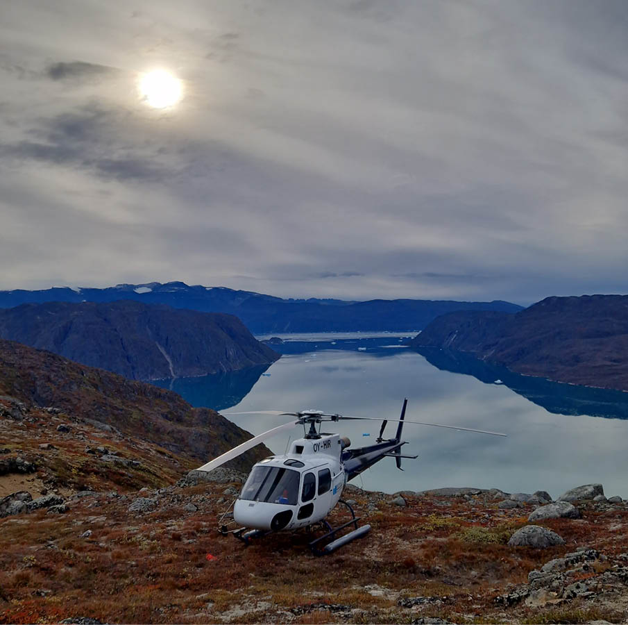 A helicopter is parked on a rocky hillside with a lake in the background. AI generated content