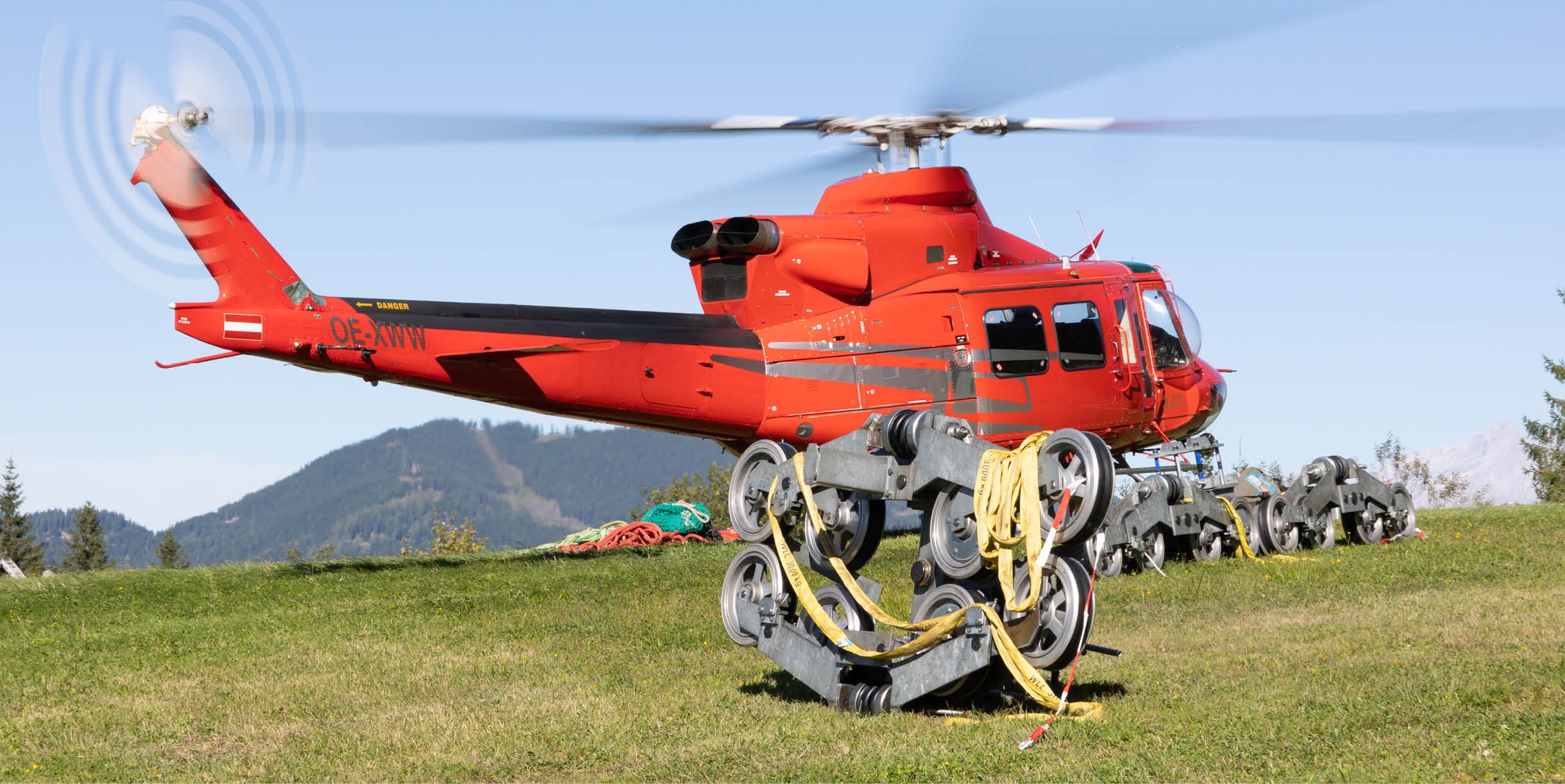 A red helicopter with a large blade is parked on a grassy field. AI generated content