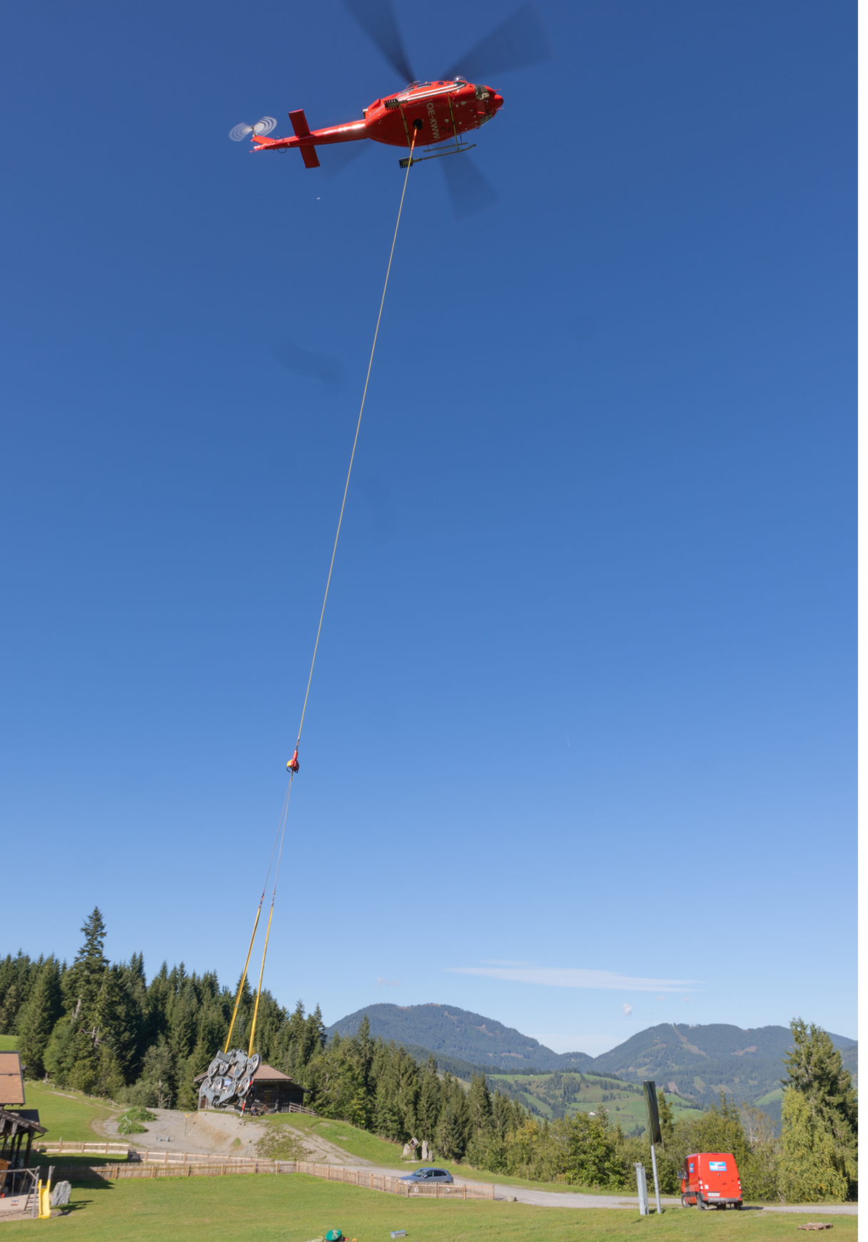 A red helicopter is flying over a green field with a red truck parked below. AI generated content