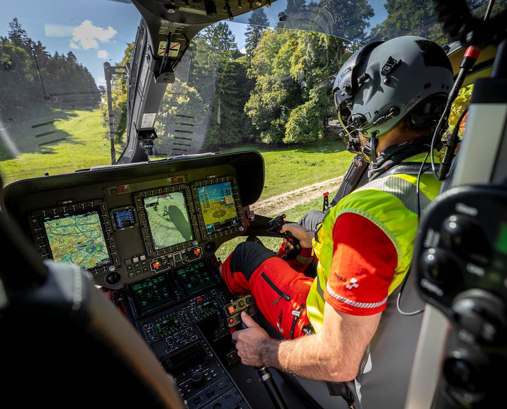 A man is sitting in a helicopter cockpit, wearing a yellow vest and a helmet. AI generated content